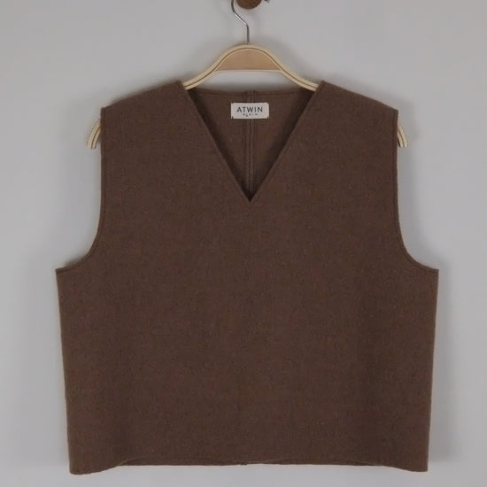 Brown boiled wool vest on a hanger against a light grey background