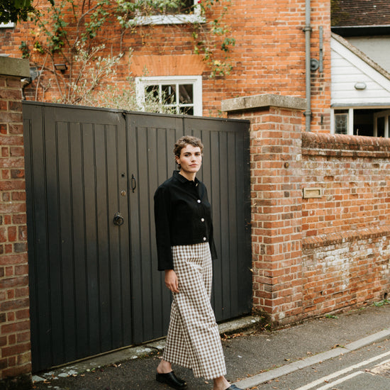 women in street setting wearing black jacket and wide leg trousers in brown gingham