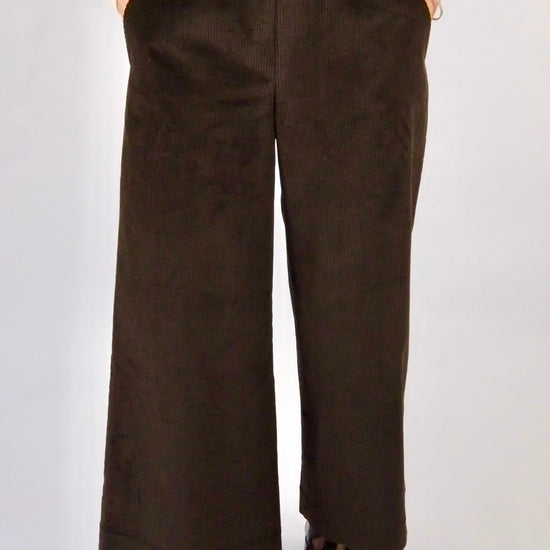 Woman wearing brown cord wide leg trousers against a white background