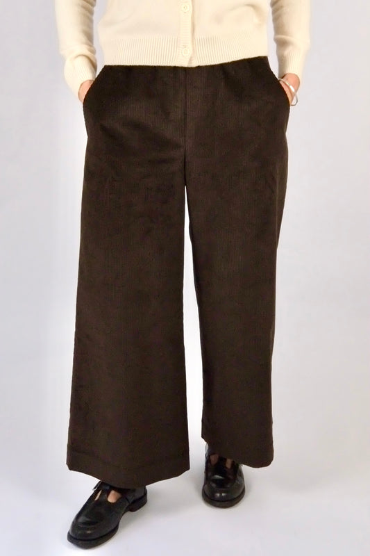 Woman wearing brown cord wide leg trousers against a white background
