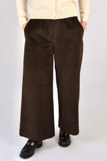 Woman wearing brown cord wide leg trousers against a white background