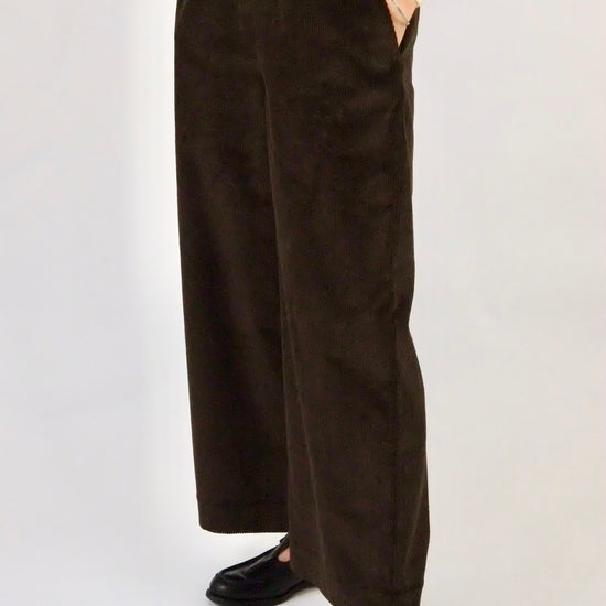 Woman wearing brown cord wide leg trousers against a white background