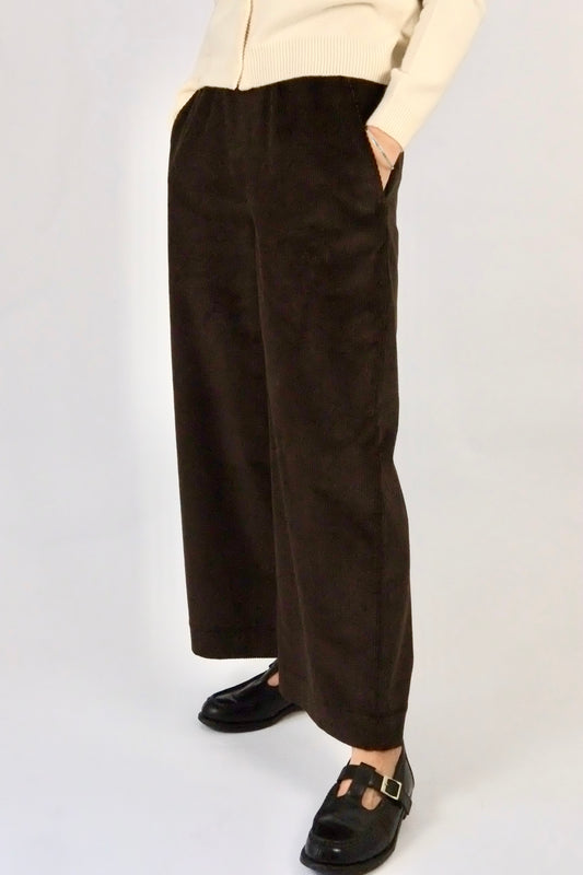 Woman wearing brown cord wide leg trousers against a white background