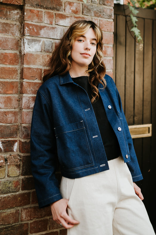Person wearing a blue denim jacket against a brick wall