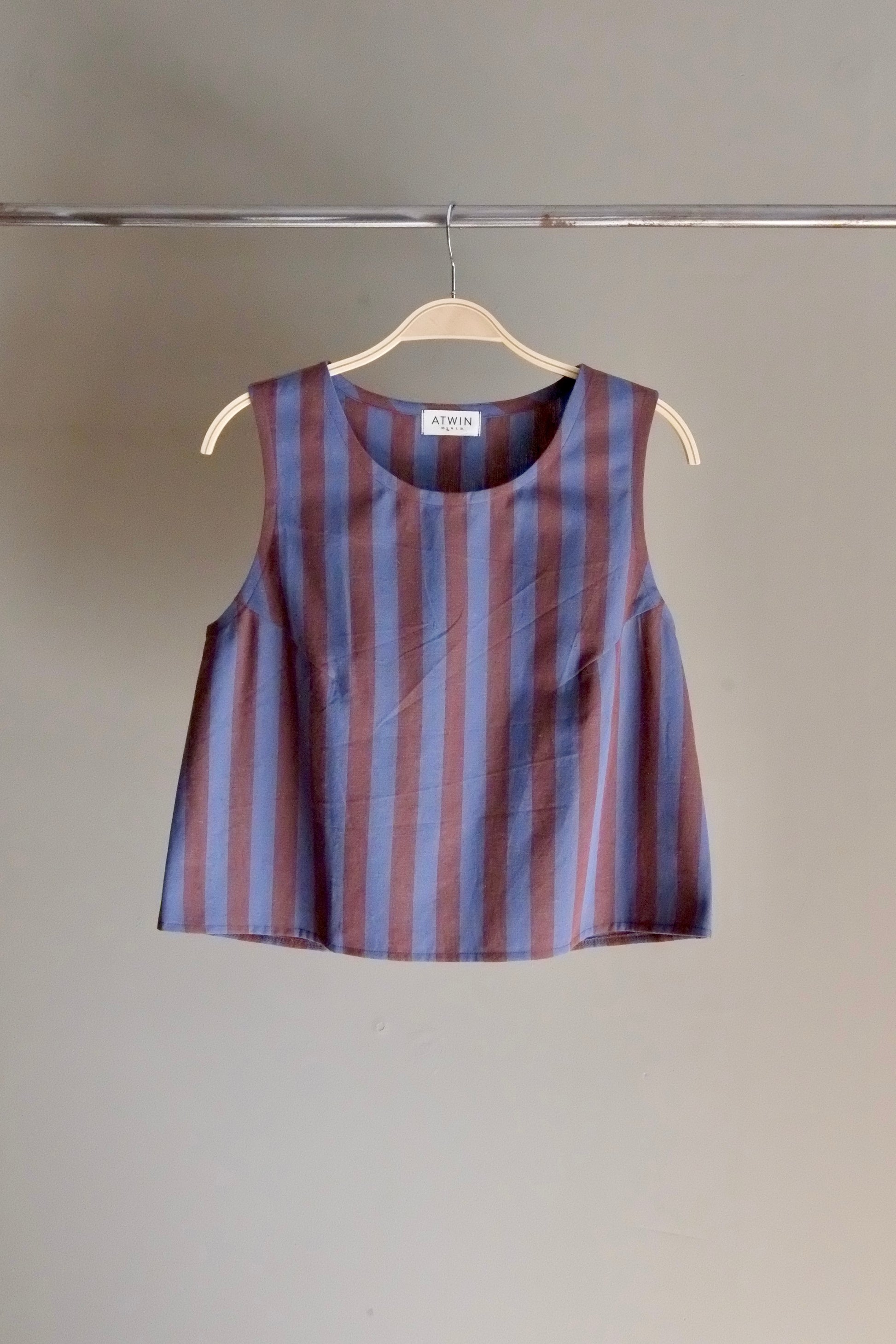 Striped sleeveless top on a hanger against a plain background