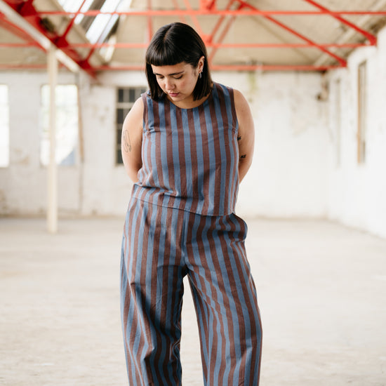 Person wearing a striped co-ord in an industrial setting with red beams.