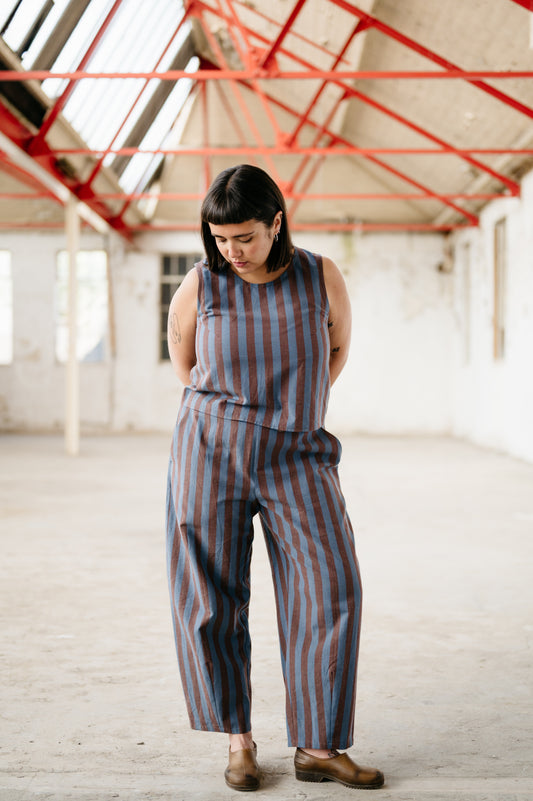 Person wearing a striped co-ord in an industrial setting with red beams.