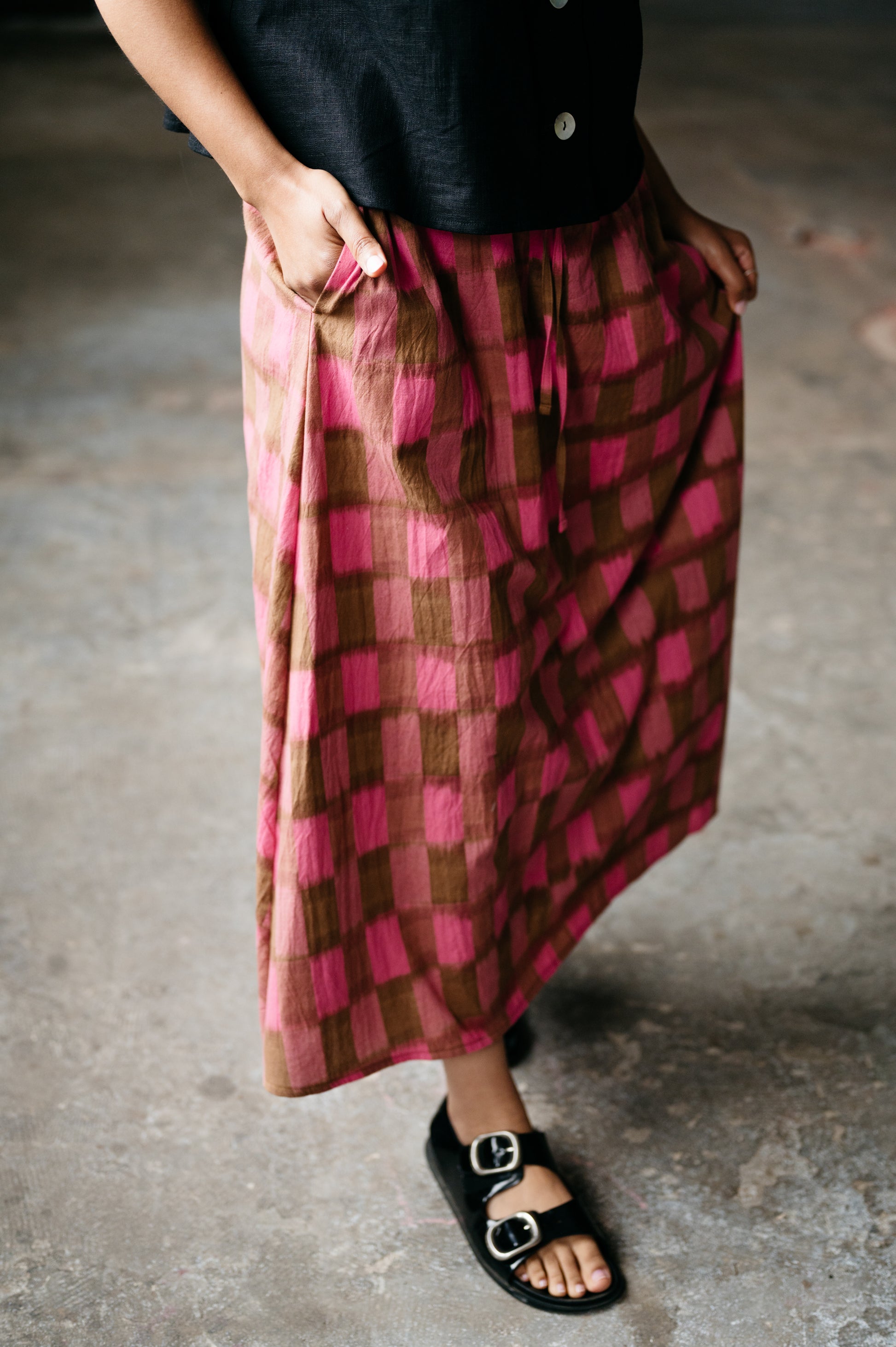 Person wearing a pink and brown checkered skirt with a blurred background