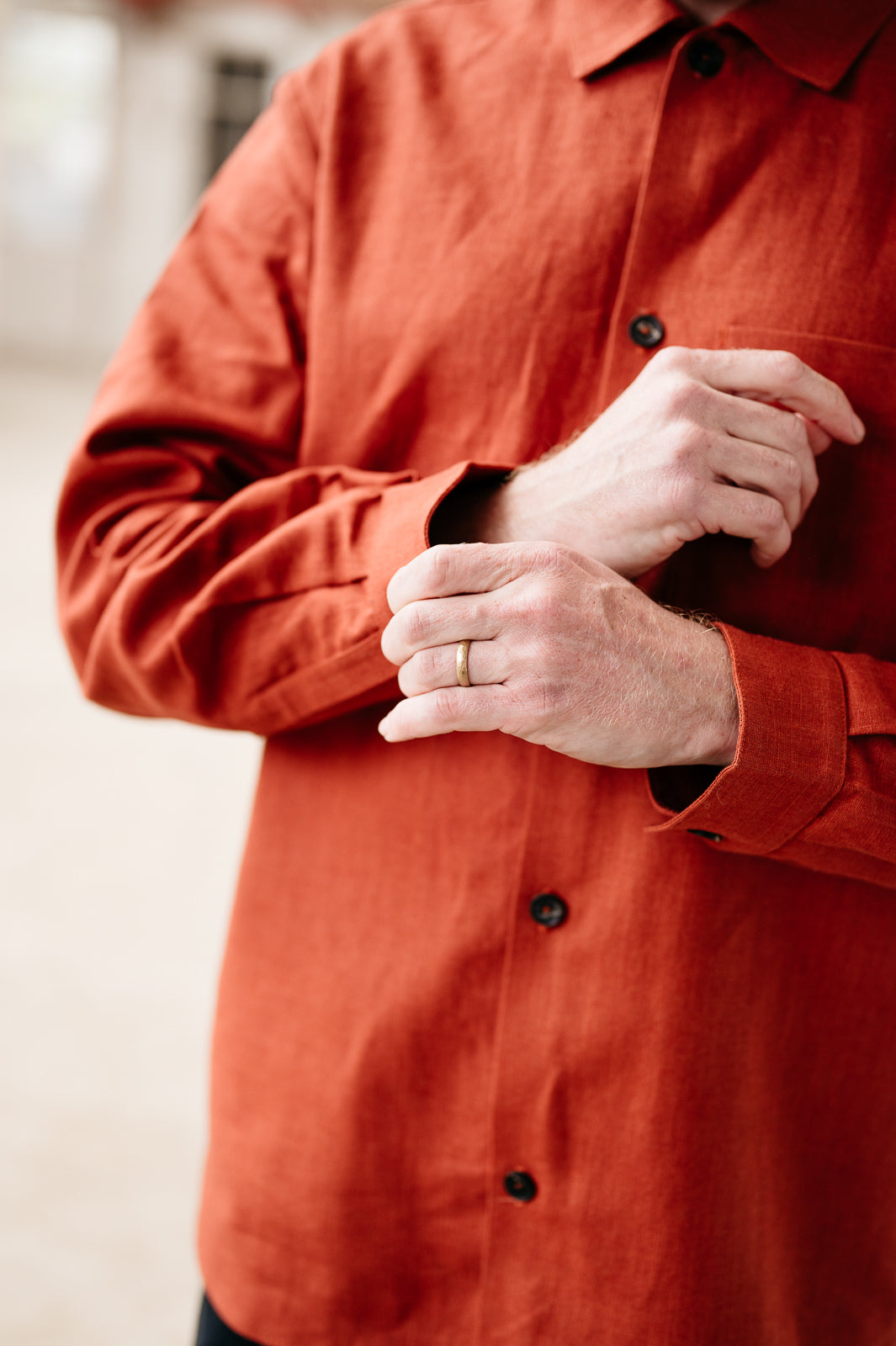 Person wearing a rust coloured shirt with buttons, focusing on the chest area.