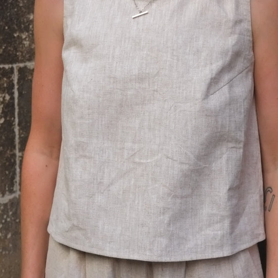 woman wearing a cream coloured sleeveless top 