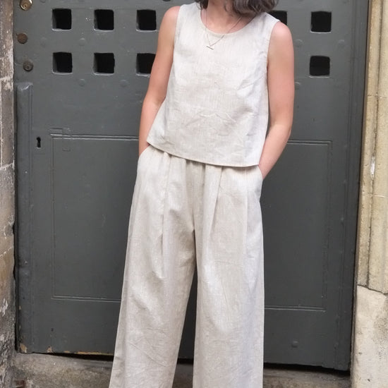 woman wearing a cream coloured sleeveless top and trousers in front of an old door