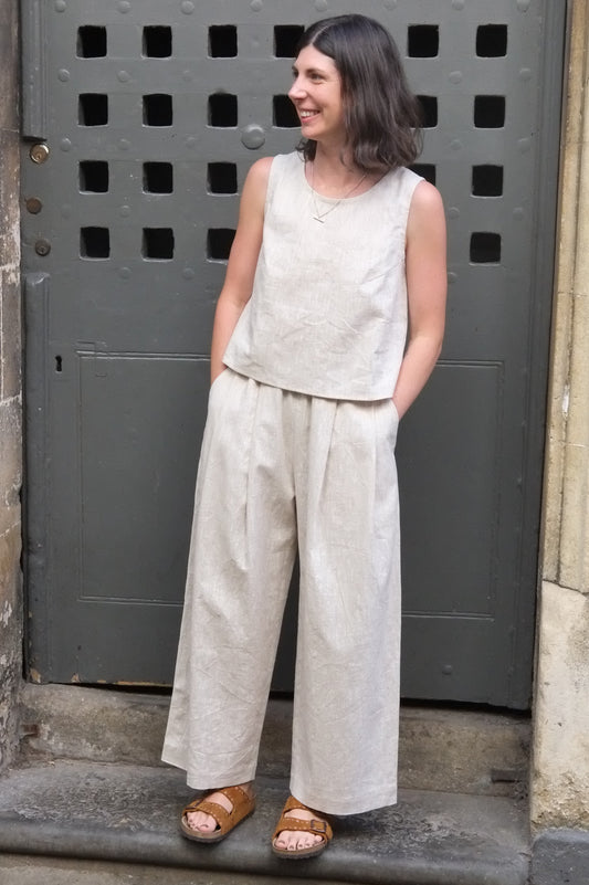 woman wearing a cream coloured sleeveless top and trousers in front of an old door