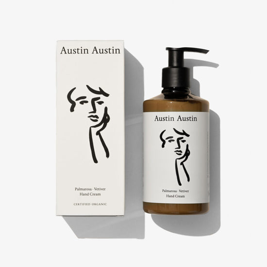 A bottle of handcream with a black and white face illustration on a white background 