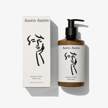 A bottle of handcream with a black and white face illustration on a white background 