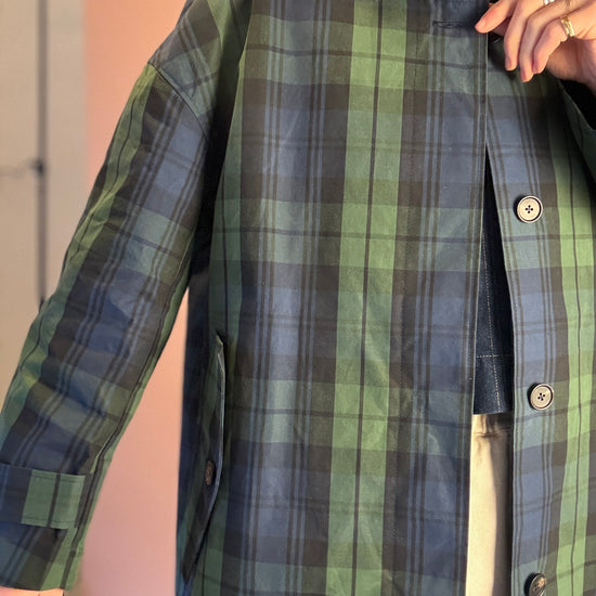 Person wearing a green and blue plaid coat indoors