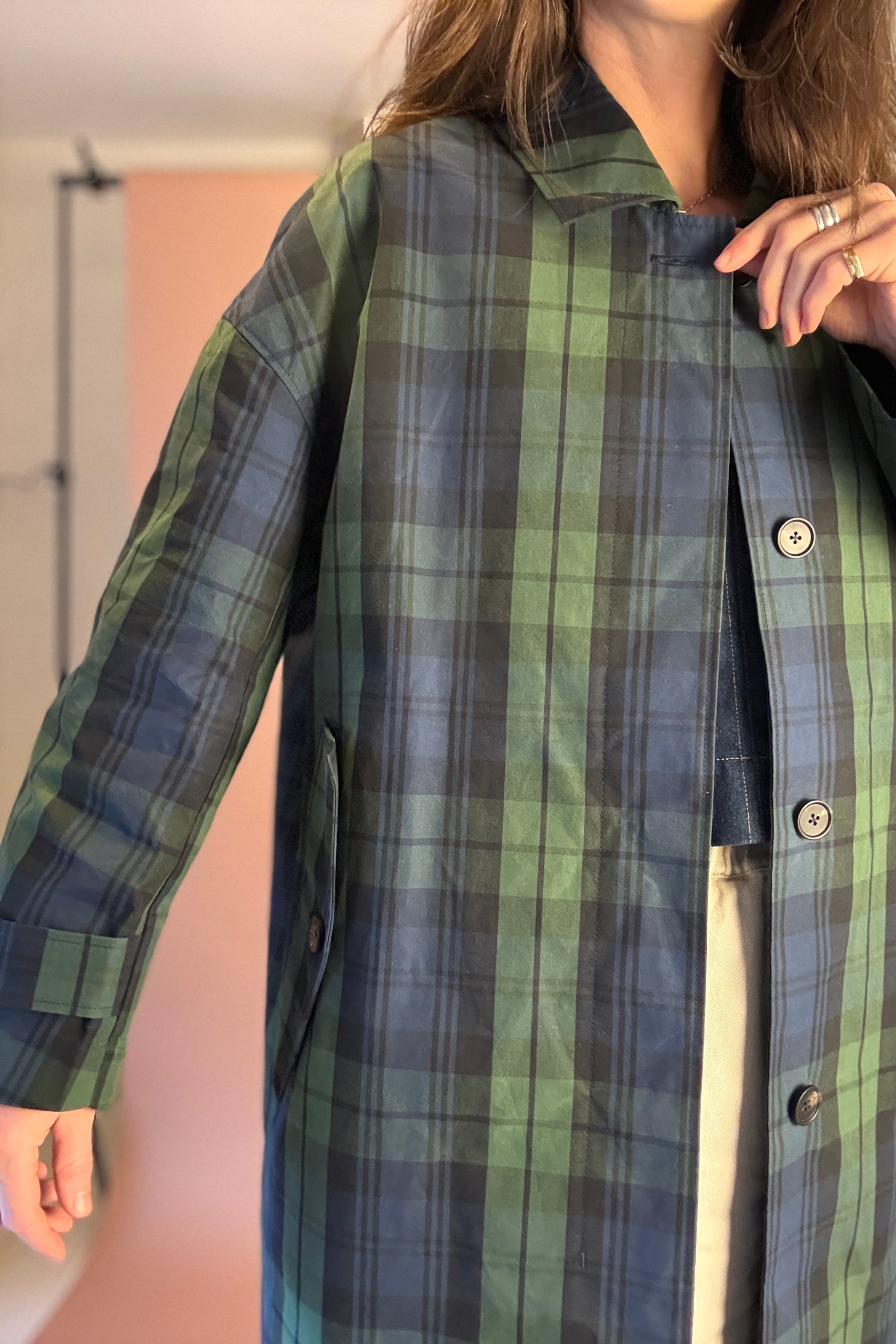 Person wearing a green and blue plaid coat indoors