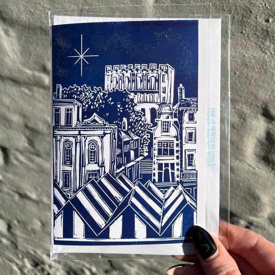 Greeting card with blue and white architectural illustration held against a textured gray background