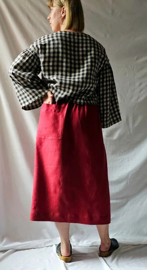Person wearing a checkered top and red skirt against a plain background