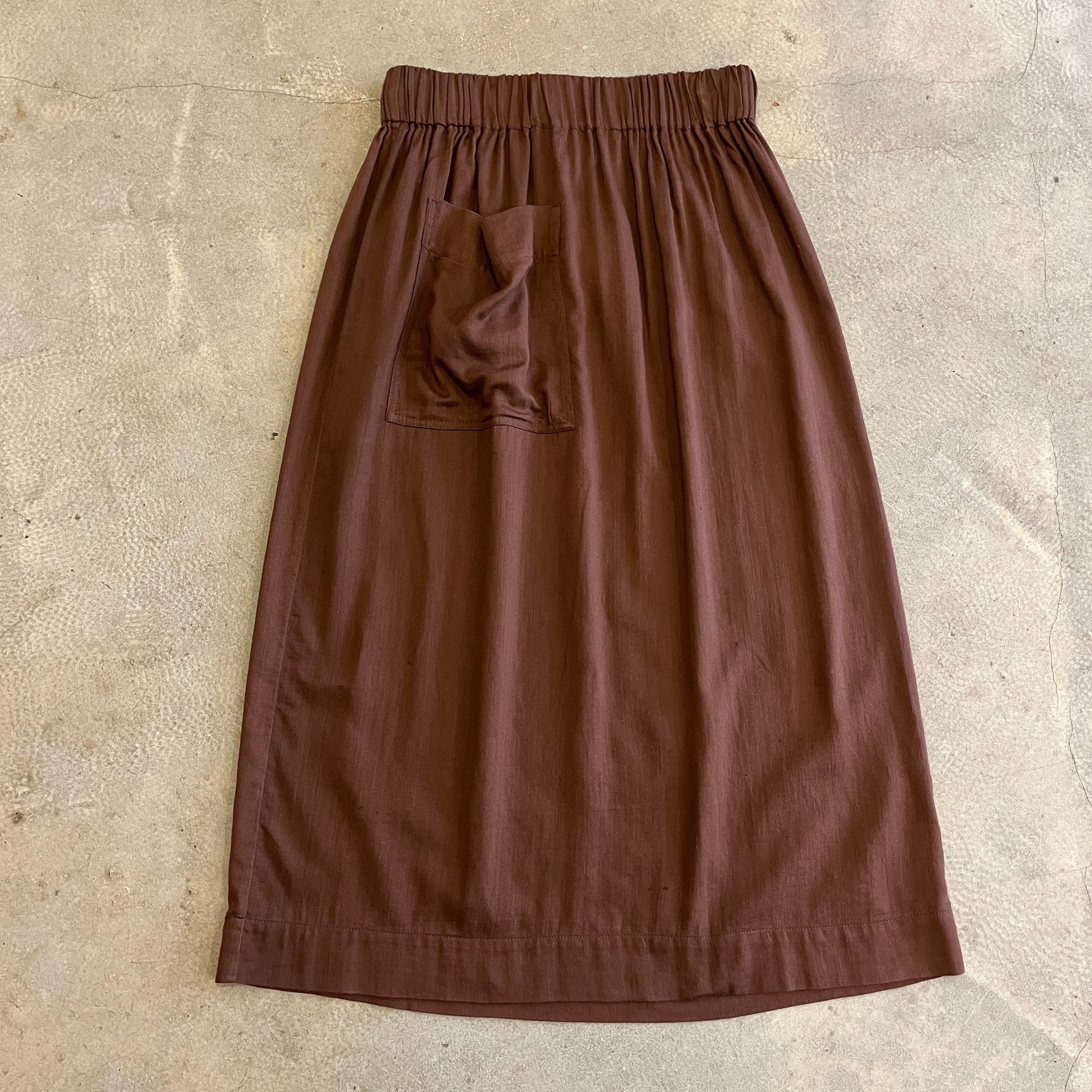Brown skirt with a pocket on a beige stone surface