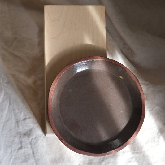 Wooden block with a metal bowl on a textured fabric background plate brown ceramics
