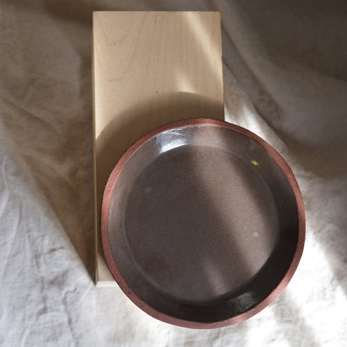 Wooden block with a metal bowl on a textured fabric background plate brown ceramics