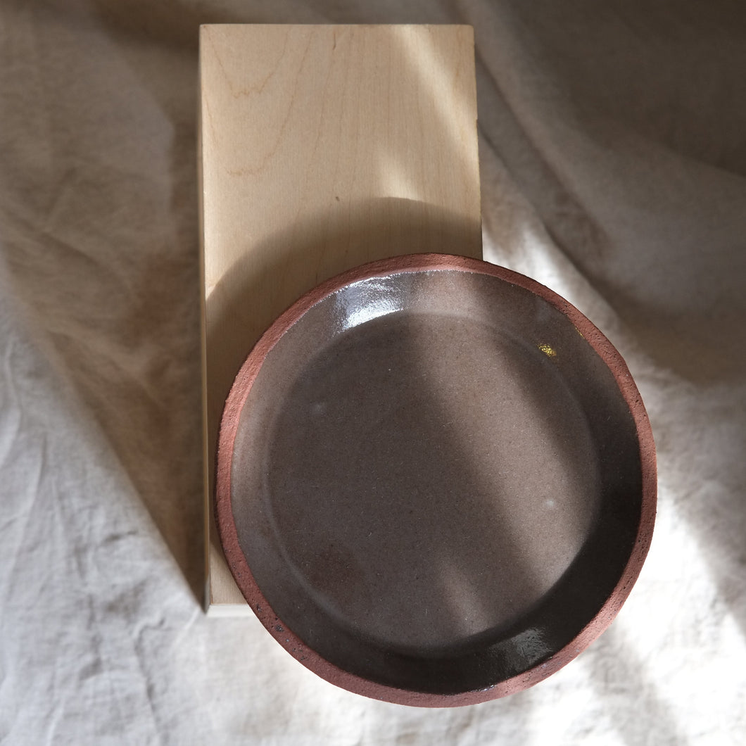 Wooden block with a metal bowl on a textured fabric background plate brown ceramics