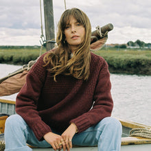 Load image into Gallery viewer, A woman sitting on a boat wearing a maroon jumper outdoors 
