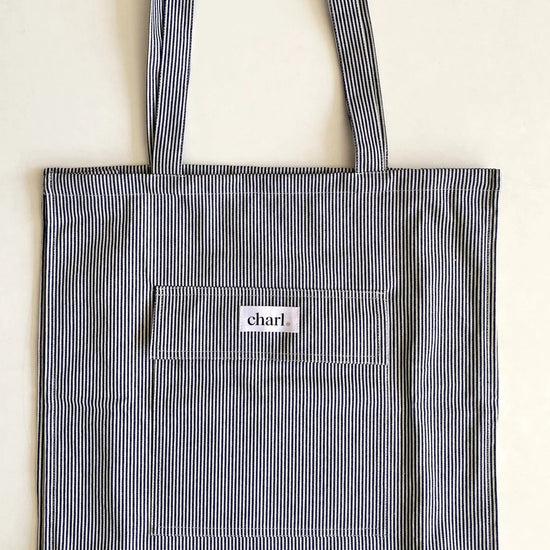 Blue striped tote bag with a visible brand logo on a light background
