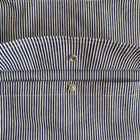 Close-up of a navy and white striped bag with two gold buttons.