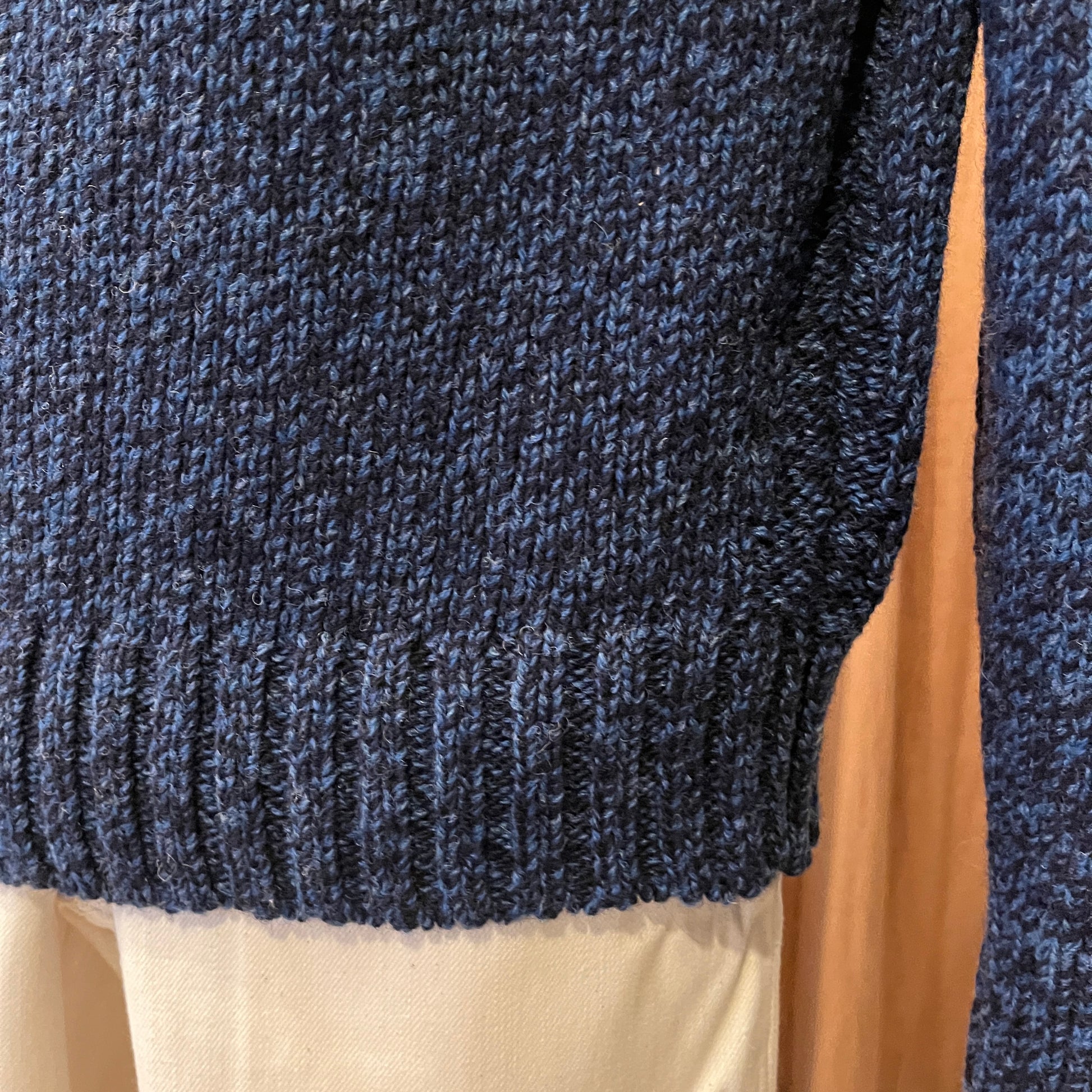 Close-up of a blue knitted sweater on a mannequin with a beige background