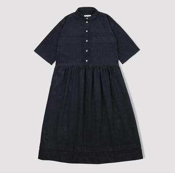 Navy corduroy dress with short sleeves and a button down front with a collar and gathered waist  on a light gray background