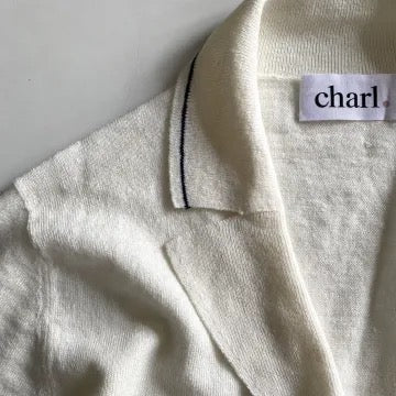 Close-up of a white top with a brand tag on a light gray background
