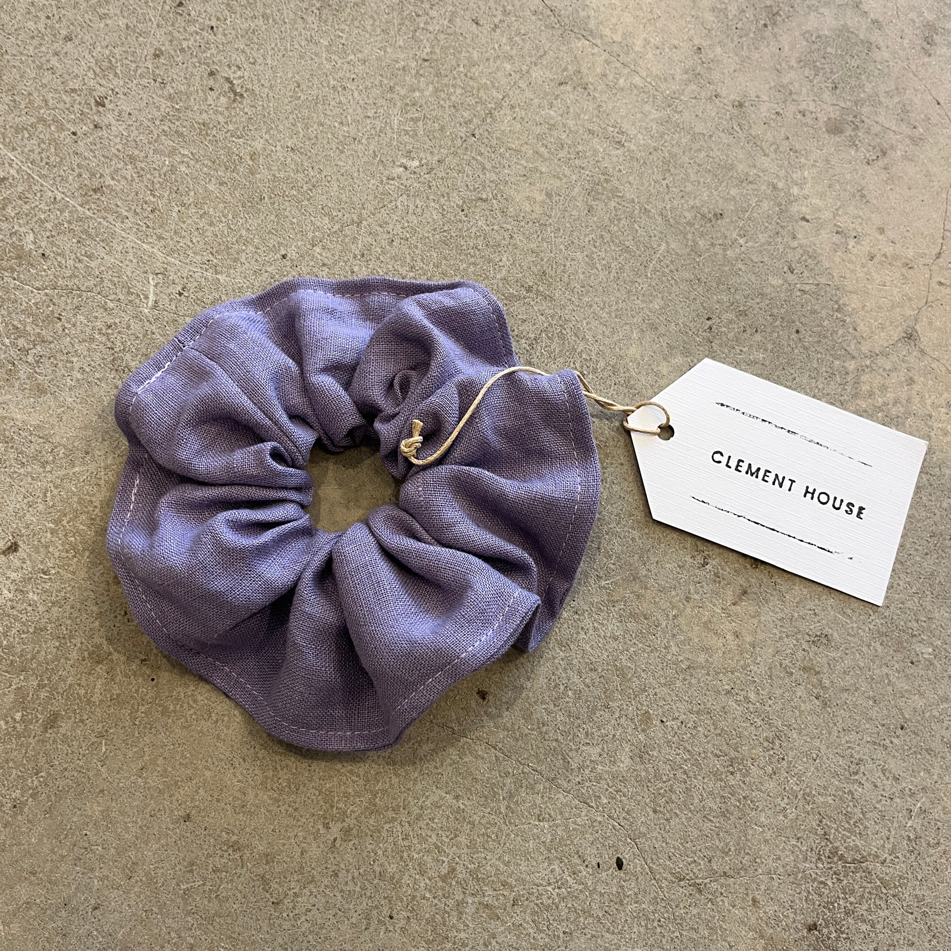 Purple scrunchie with a tag on a beige surface