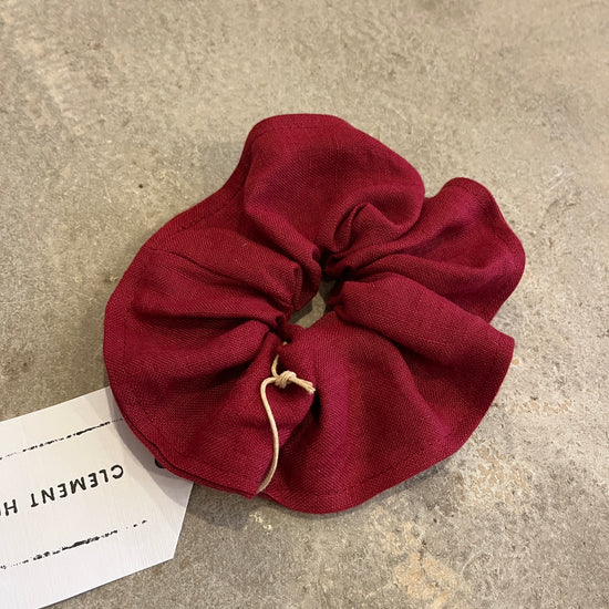 Red scrunchie on a textured surface with a label underneath