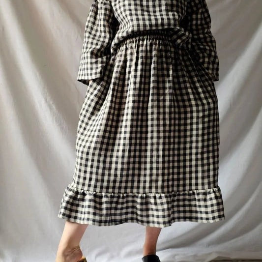 Woman wearing a checkered skirt and top against a white background