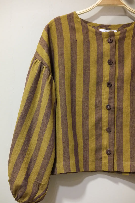 A close-up of a striped garment with long gathered sleeves, featuring horizontal mustard yellow and brown stripes with a buttoned neckline.