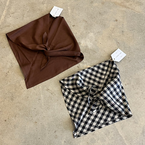Brown and black and white checkered neck tie scarves on a concrete surface