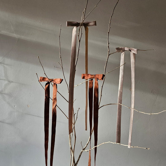 Silk bows on a tree branch with a neutral background 