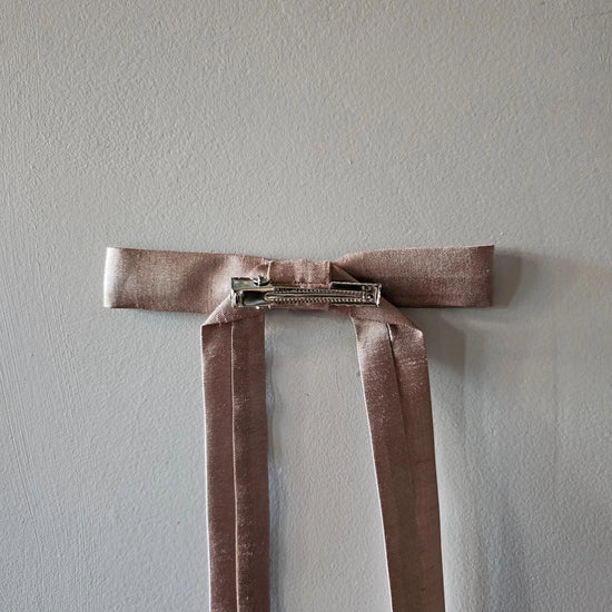 Brown velvet ribbon with a clip on a light gray background