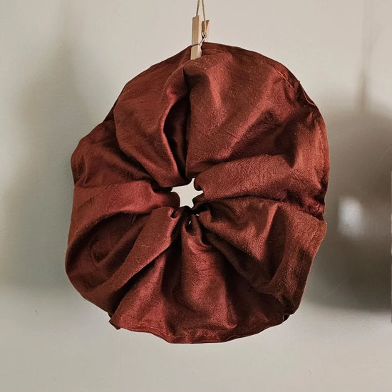 A red silk scrunchie on a neutral background 