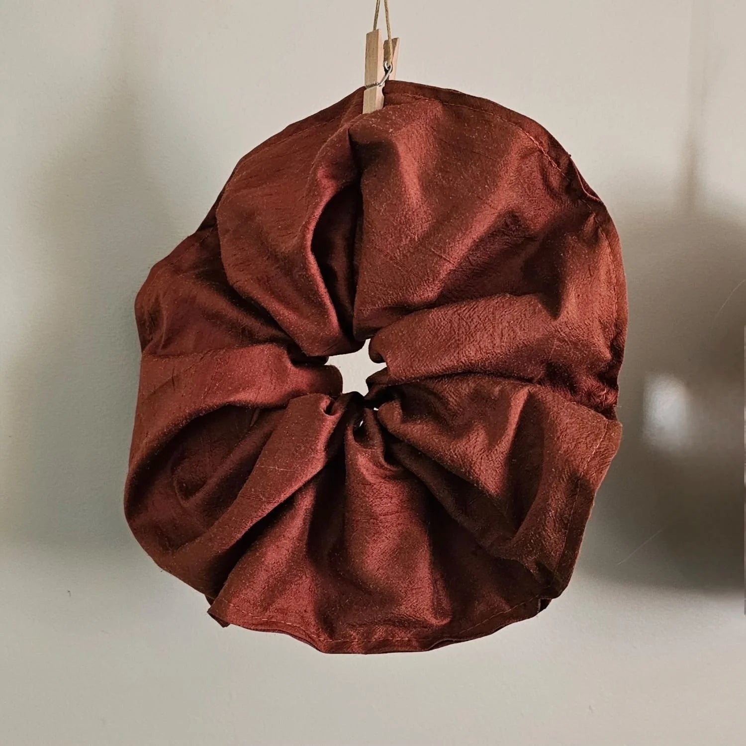 A red silk scrunchie on a neutral background 