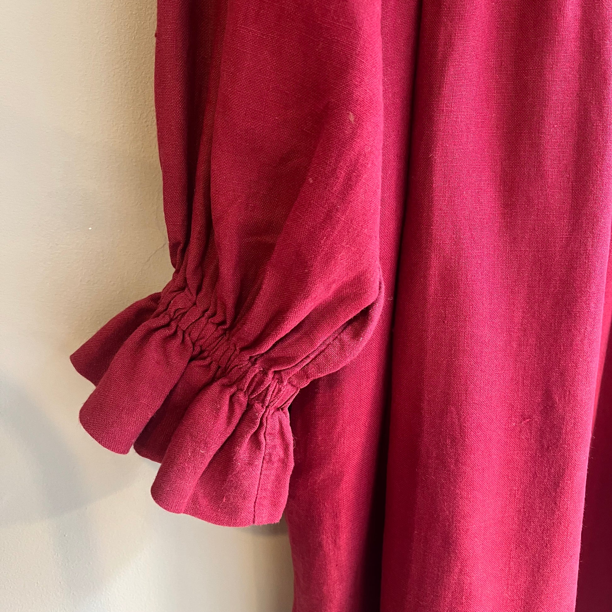 Close-up of a red garment with puffed sleeves on a neutral background
