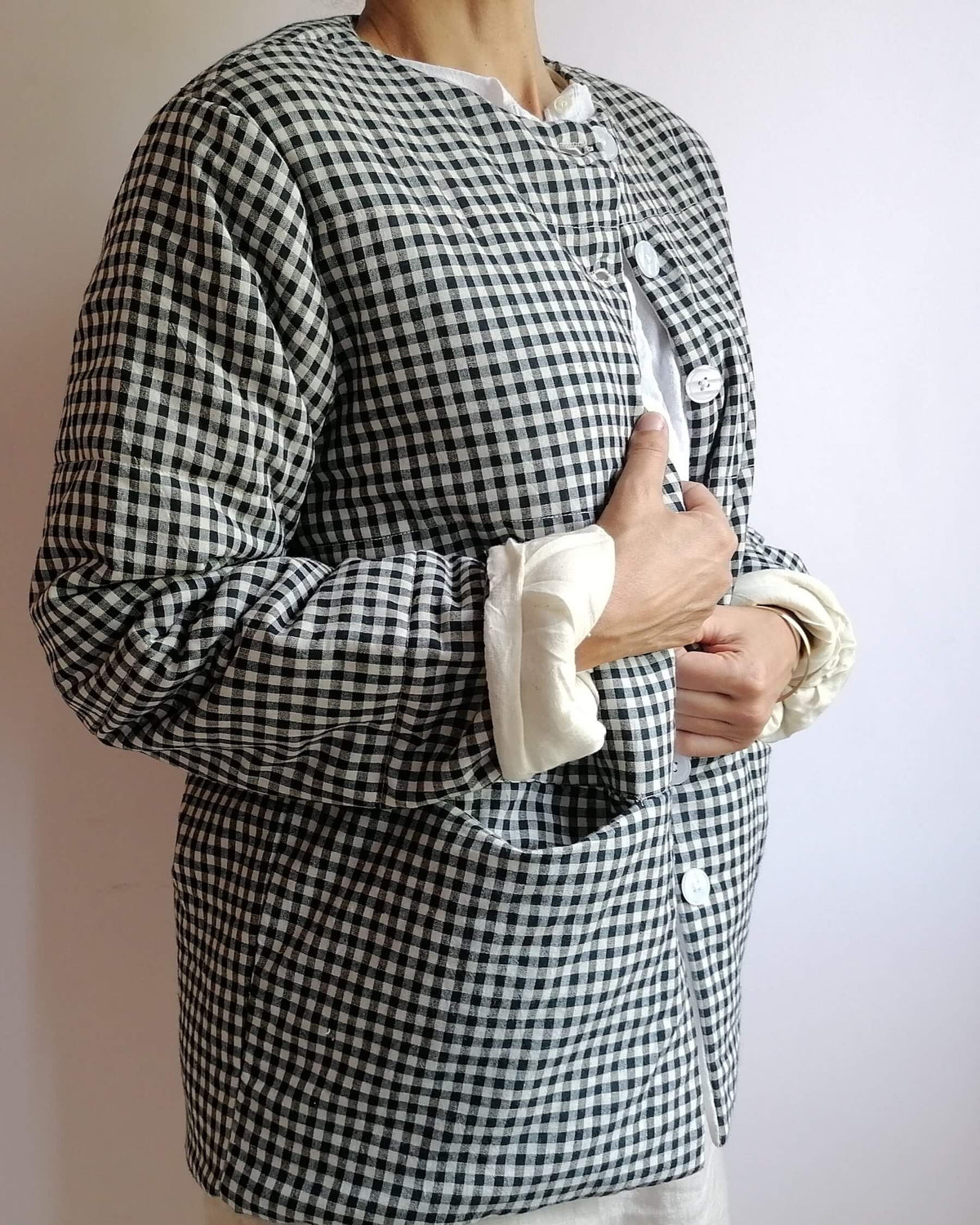A person wearing a black and white gingham check long-sleeve button-up shirt with rolled-up cuffs showing a white lining, photographed against a plain light background.