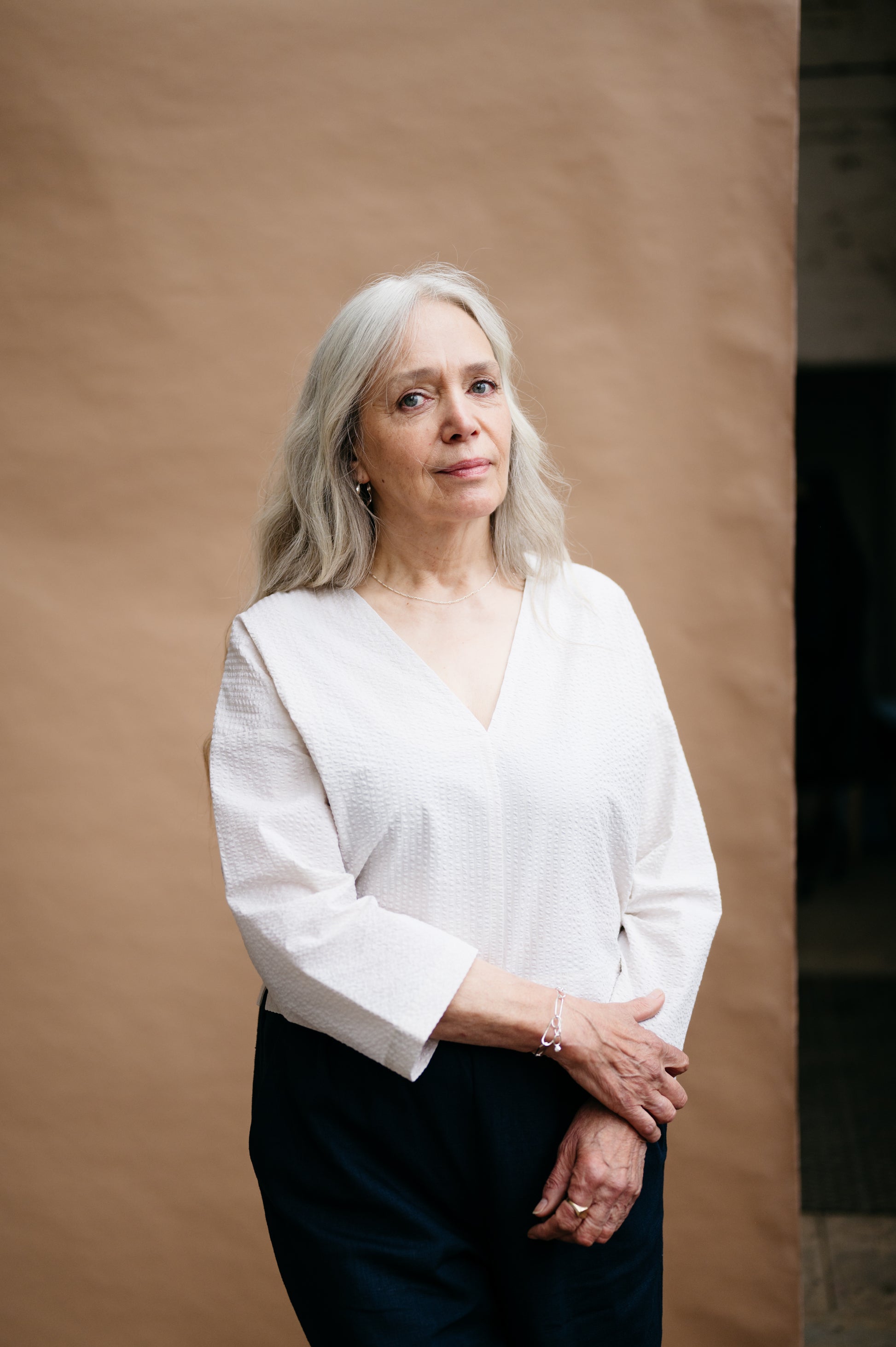 Woman wearing a white blouse against a brown background