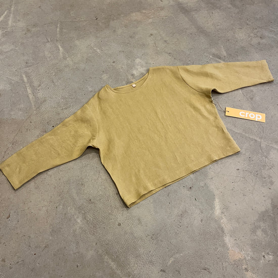Yellow long-sleeve shirt on a grey concrete floor with a brand tag.
