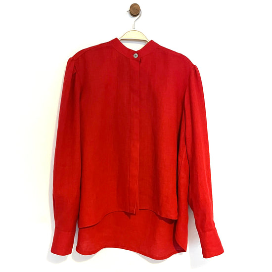 Red long sleeve collarless blouse on a hanger against a white background