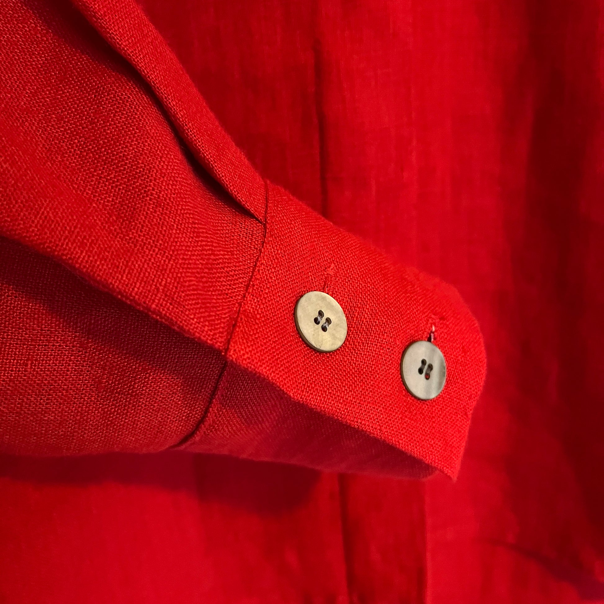 Close-up of a red shirt with double button detail sleeve and visible buttons.
