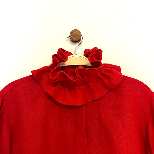 Red blouse with ruffled collar on a wooden hanger against a white background