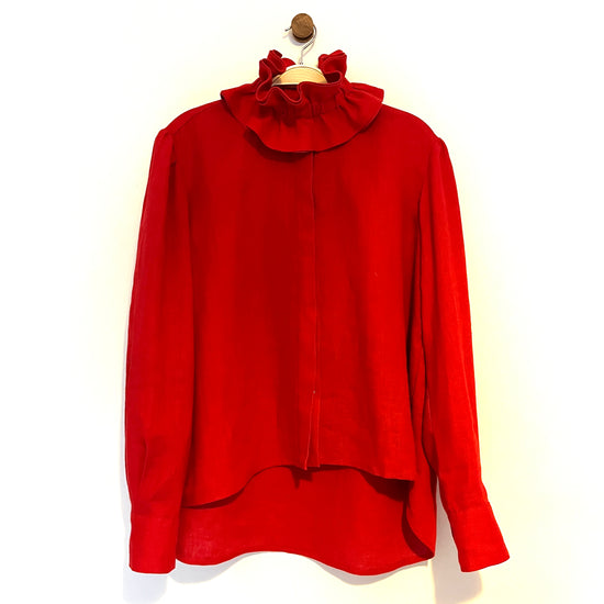 Red blouse with a ruffled collar on a hanger against a white background
