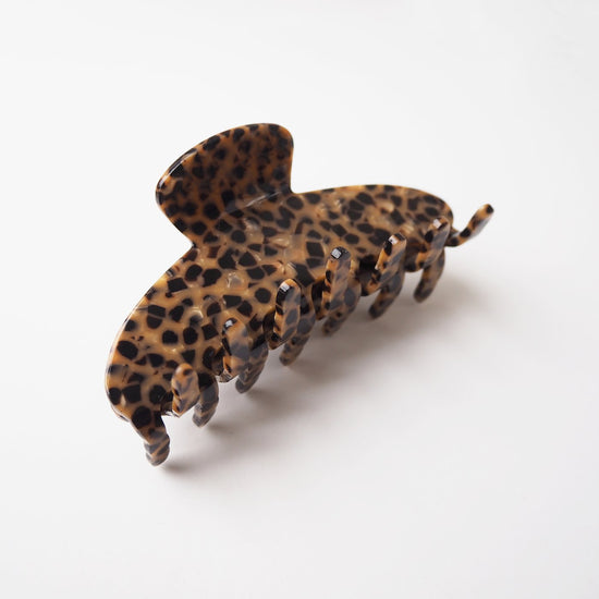 A brown hair clip with black flecks on a white background